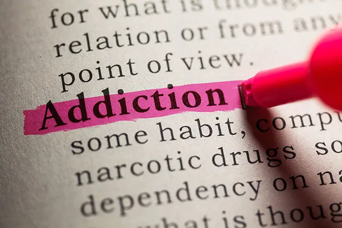 the word "addiction" is highlighted in pink in a dictionary