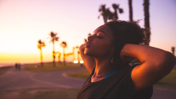 A woman enjoys a sunset near the ocean