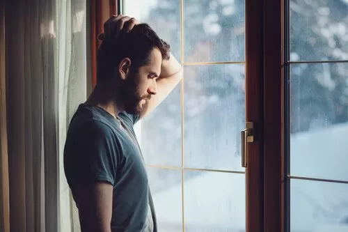 man depressed looking out a window