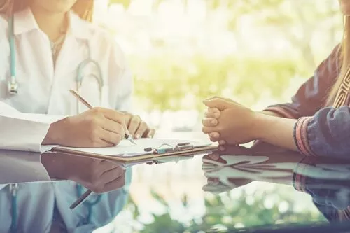 doctor taking notes while talking with a patient