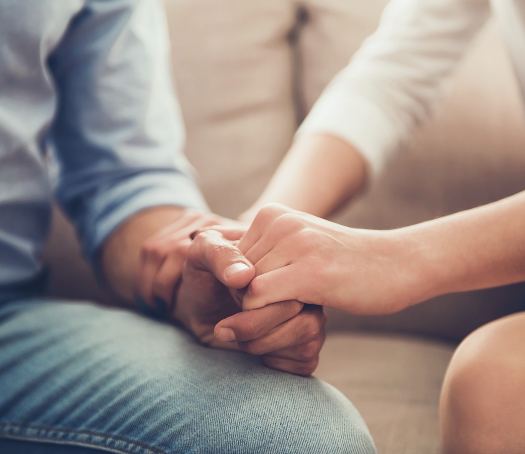 Two people supporting each other through addiction recovery by holding hands
