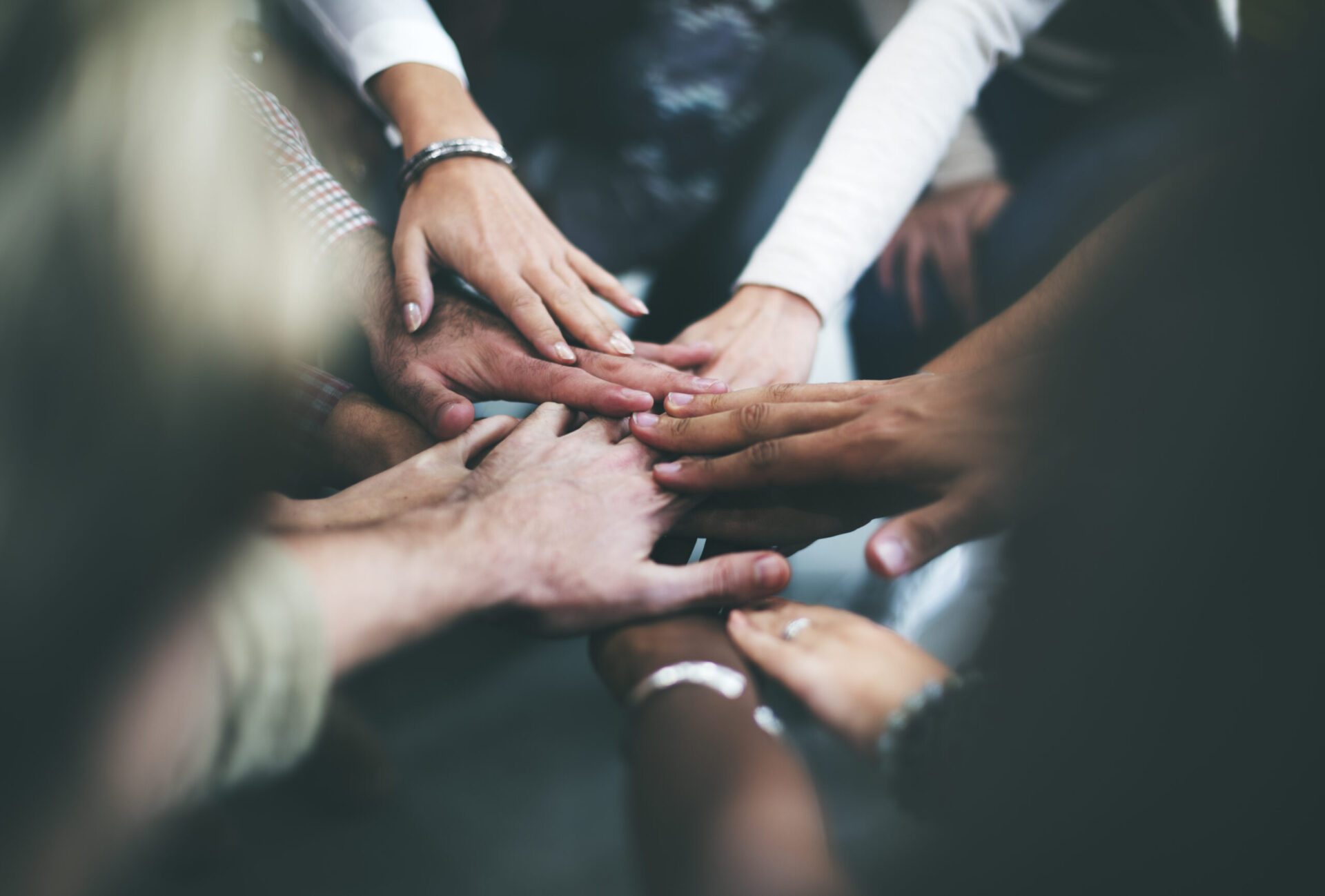 Group of people doing a team cheer at the end of an addiction recovery support group meeting
