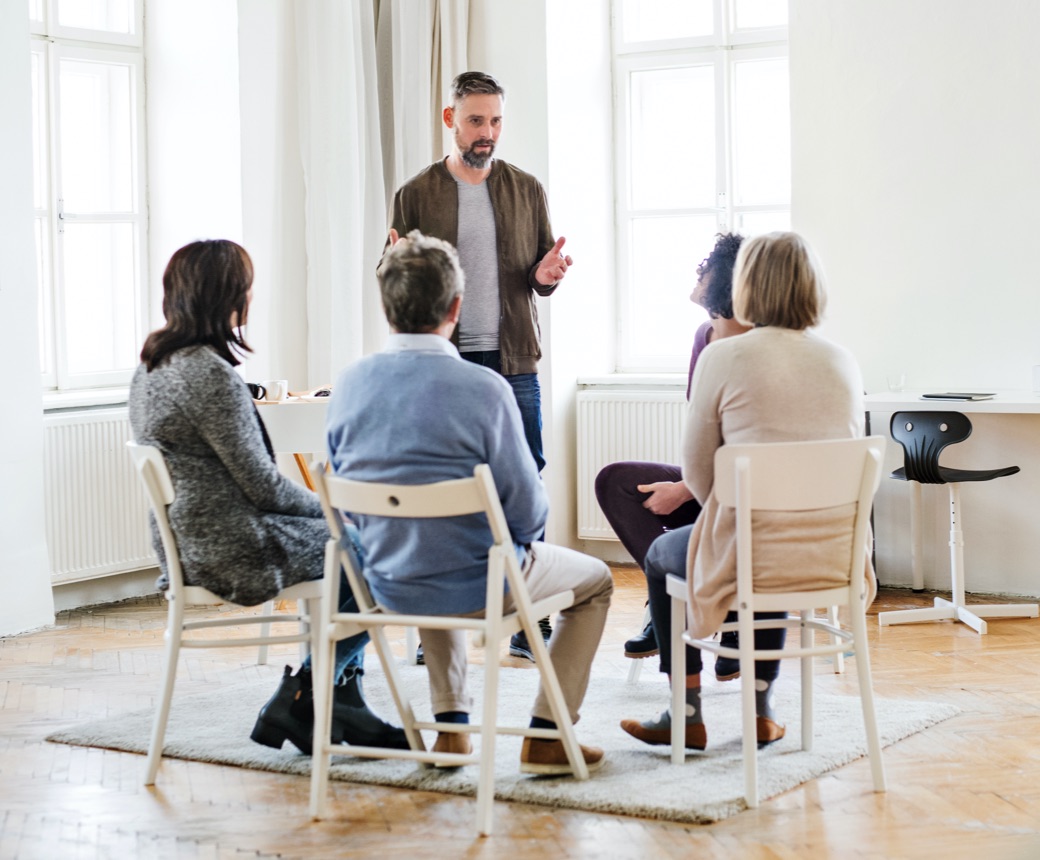 A man talking to people struggling with substance use disorders during a group therapy session