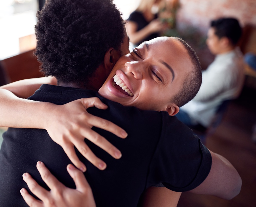 Woman happily embracing a man at an addiction recovery support group