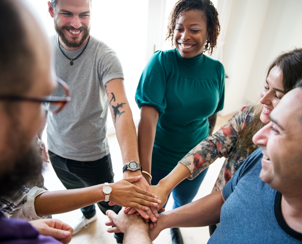 Group of people doing a team cheer at the end of an addiction recovery support group meeting