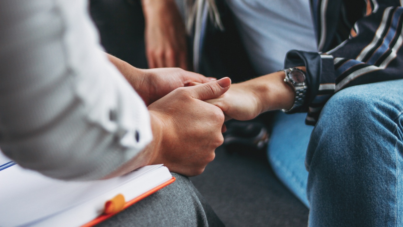 Two people supporting each other through addiction recovery by holding hands