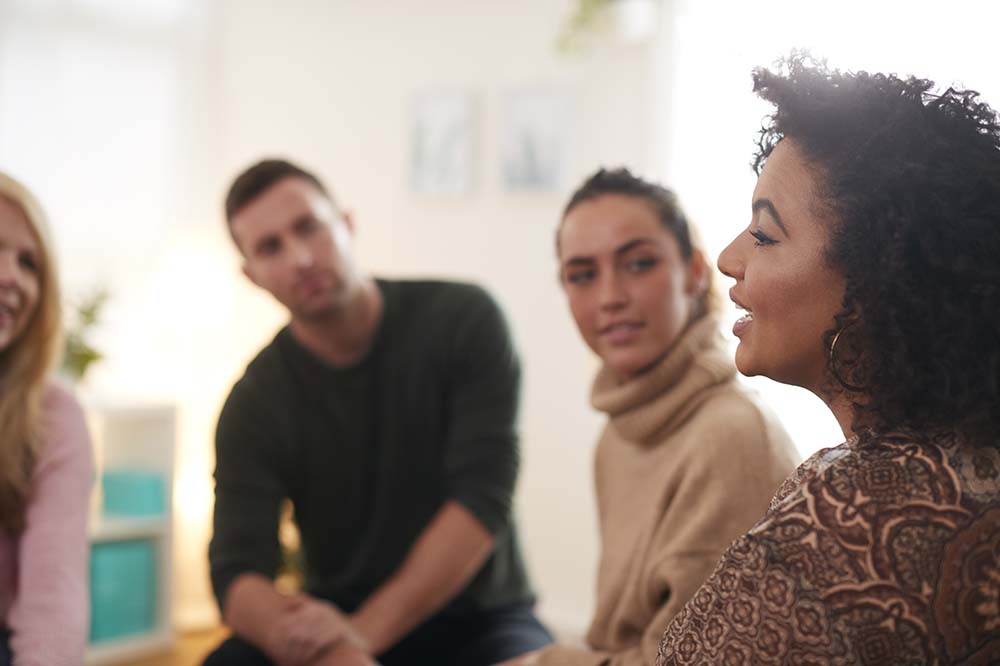 A woman speaks to her alcohol addiction support group