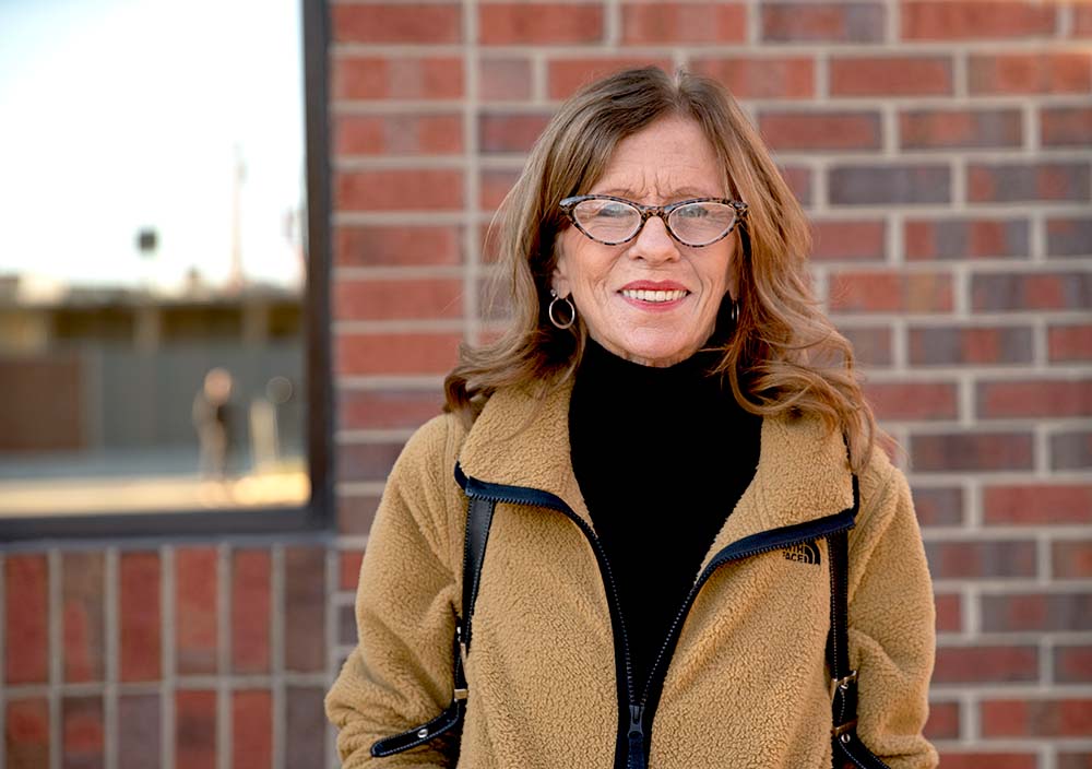 Cindy, an Eleanor Health community member, poses in front of a brick building