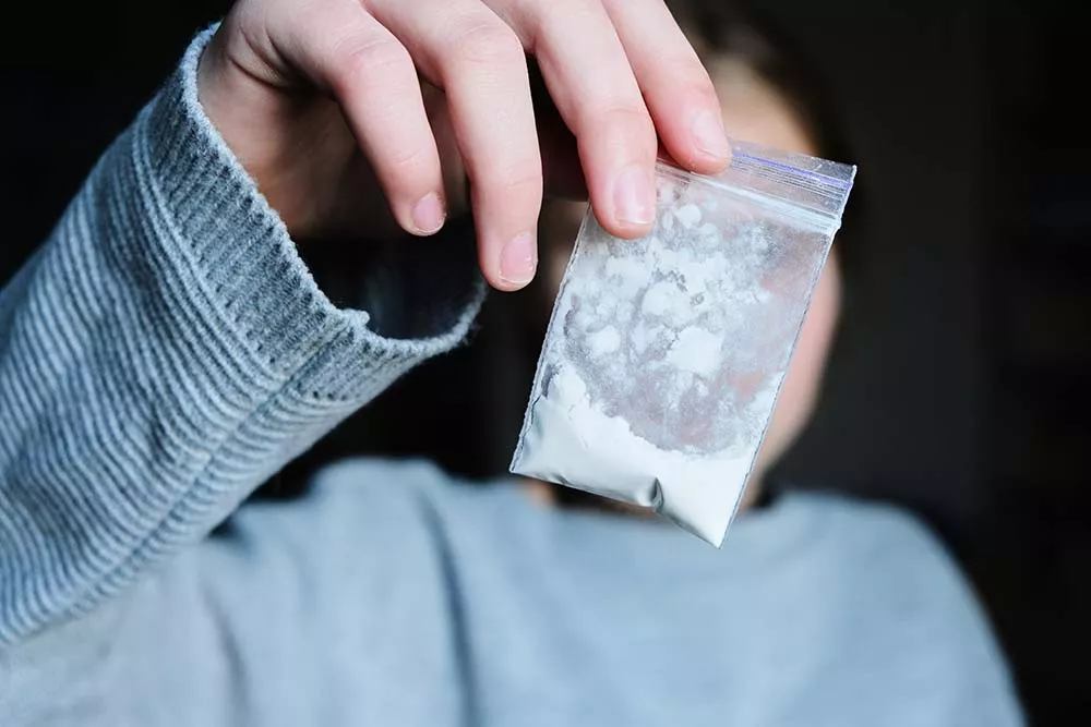 A person holds up a bag of meth in powder form