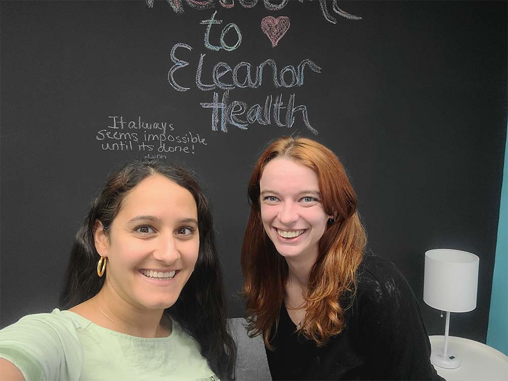 Lindsay and Sarah pose in front of a chalkboard at Eleanor Health clinic in Edison, New Jersey