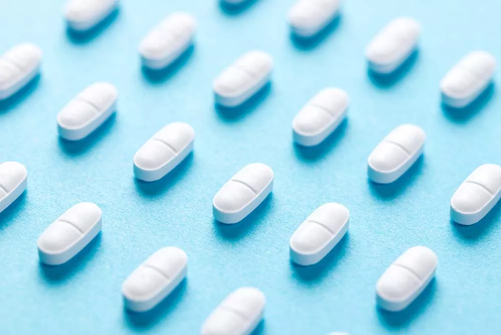 Rows of naltrexone pills on a blue background