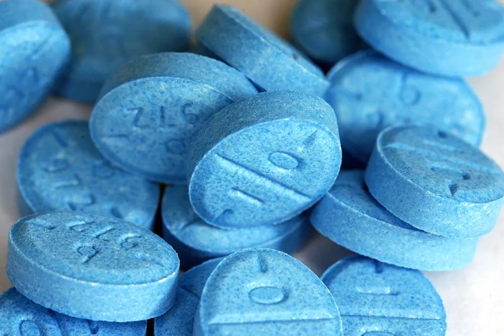 A close-up of blue adderall pills on a white background