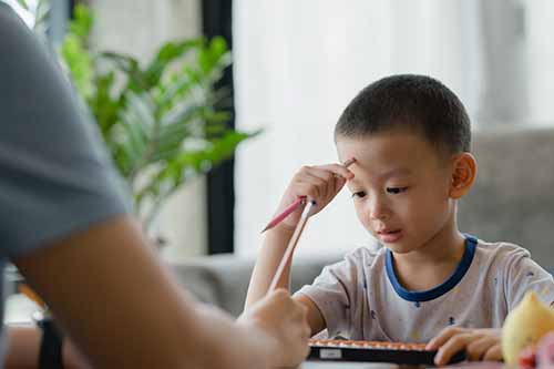 A kid showing symptoms of ADHD struggles with his homework