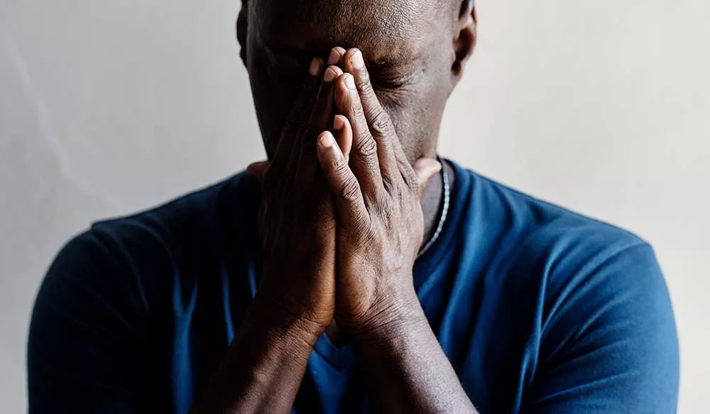 A man experiencing anxiety rubs his face with his hands