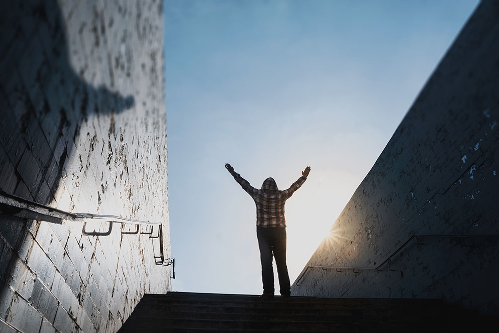 A person raises their arms at the top of a set of stairs