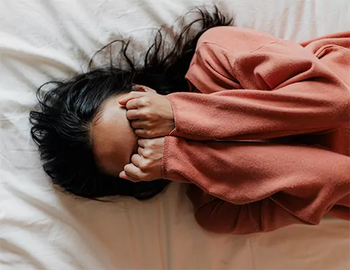 A woman experiencing anxiety covers her face with her hands