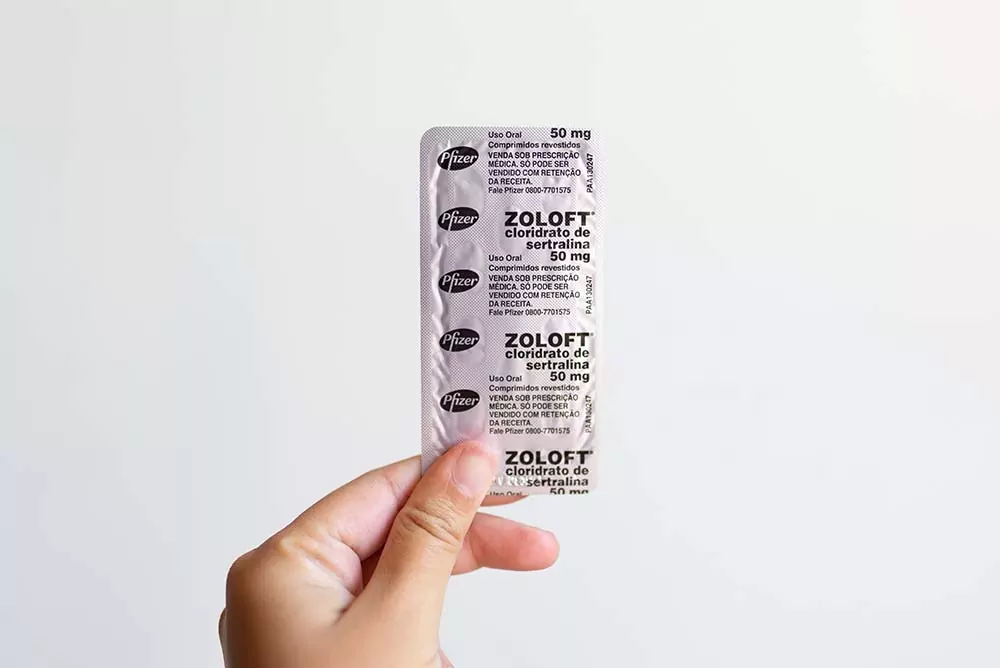 A hand holds up some packs of Zoloft or Sertraline pills