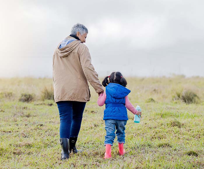 A grandmother takes a walk in a field with her granddaughter