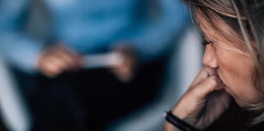 A woman bites her nails during a therapy session