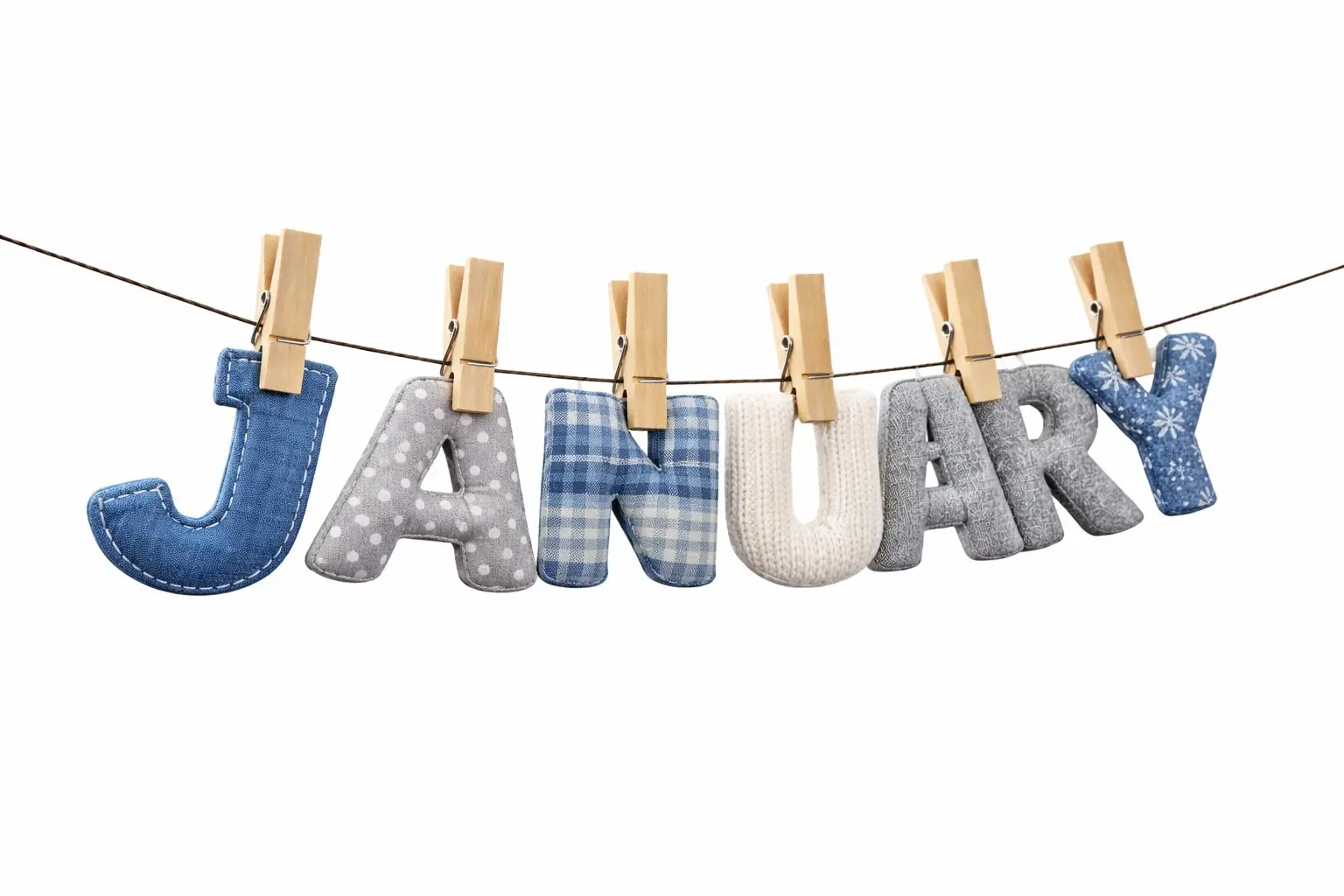 Fabric letters in cool winter tones spelling ‘JANUARY’ clipped to a clothesline with wooden clothespins.