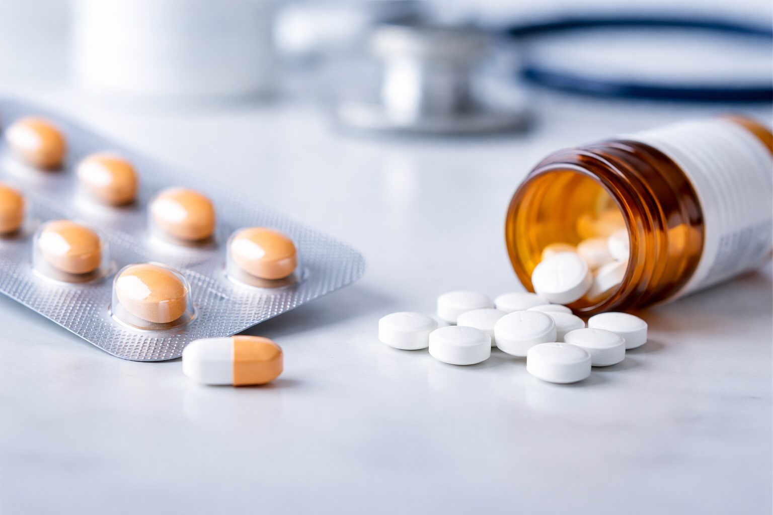 Close-up of buprenorphine tablets in a blister pack beside white methadone pills spilled from a prescription bottle, with a stethoscope in the background.